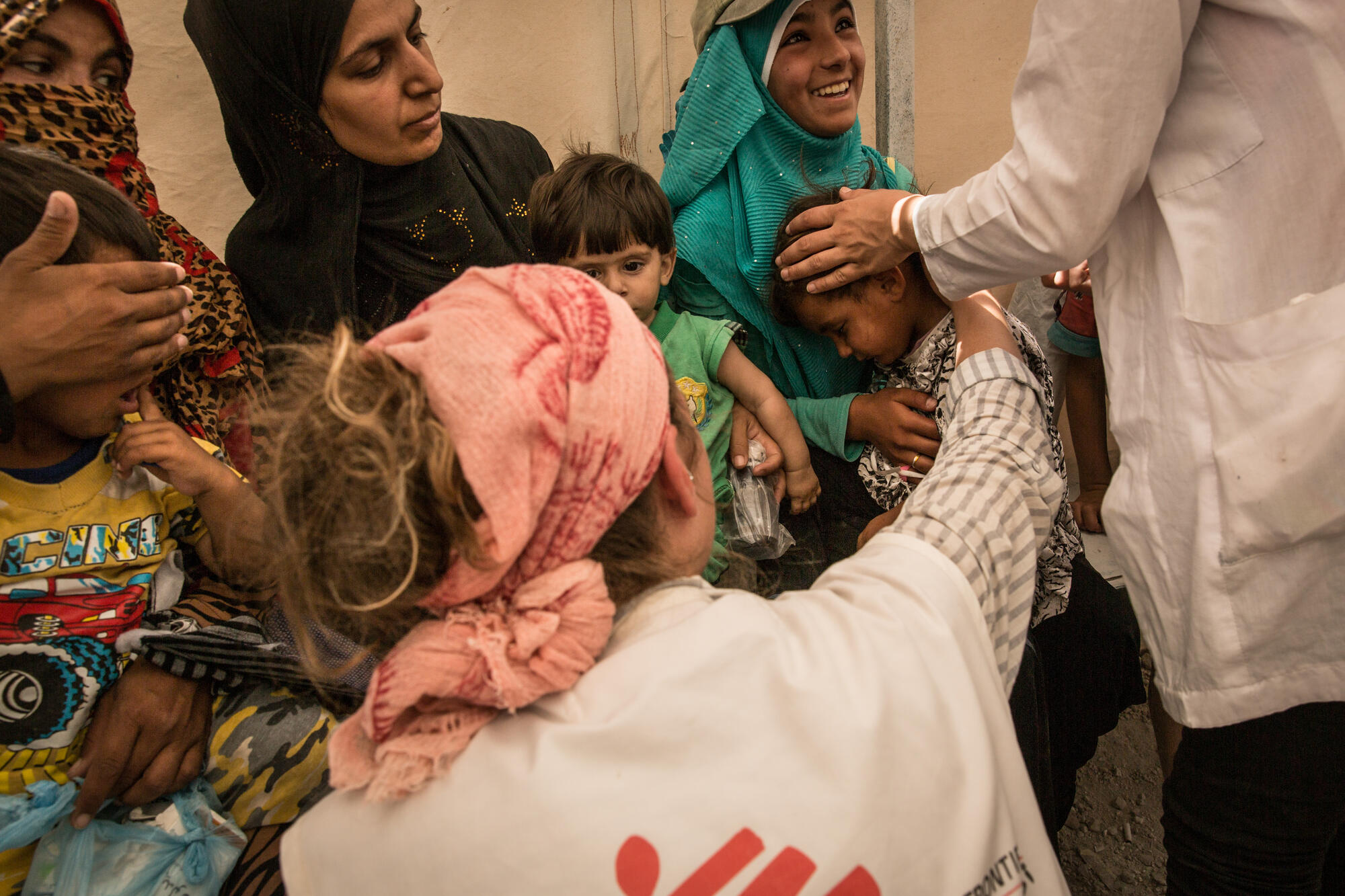 2017年7月。在敘利亞的庫爾德省艾因伊薩（AïnIssa）流離失所者營地，無國界醫生成立了診所。法國醫生埃米莉（Emilie）檢查一名正發燒的嬰兒，並進行診症。嬰兒的母親帶著他從拉卡逃到這裡。©Chris Huby
