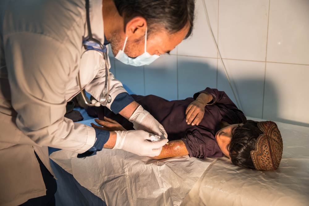 急症室<br>  一名無國界醫生醫生正在治療 8 歲的 古德拉圖拉，他的左臂長出膿瘡已達 9 天。