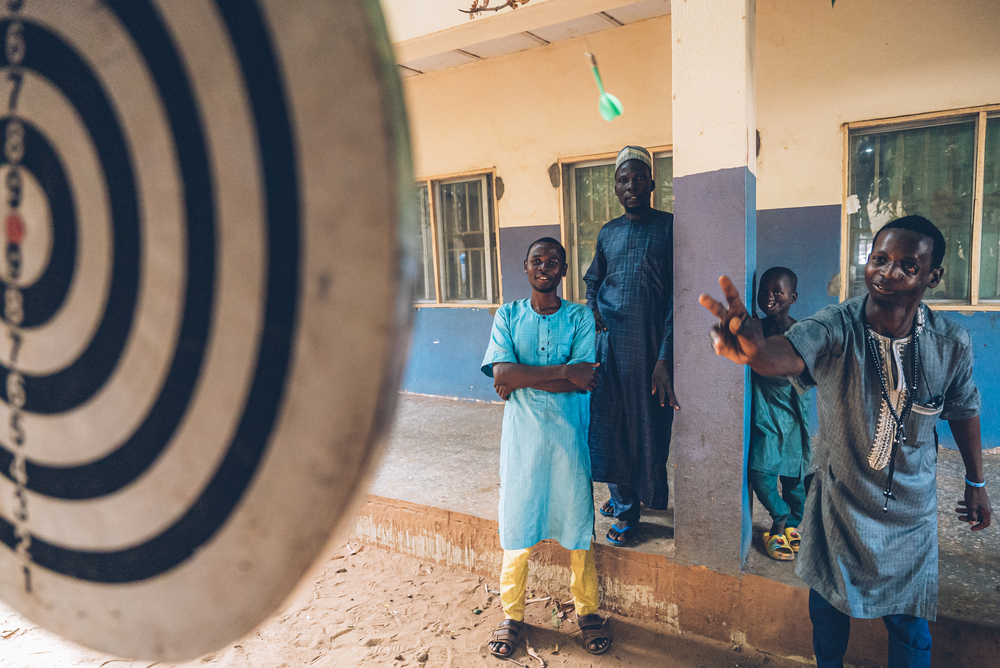Rabiu, a 20-year-old noma survivor, from Raba, Sokoto state, plays darts in the courtyard of the Sokoto Noma Hospital. Rabiu received reconstructive surgery from an MSF medical team. © FABRICE CATERINI/INEDIZ