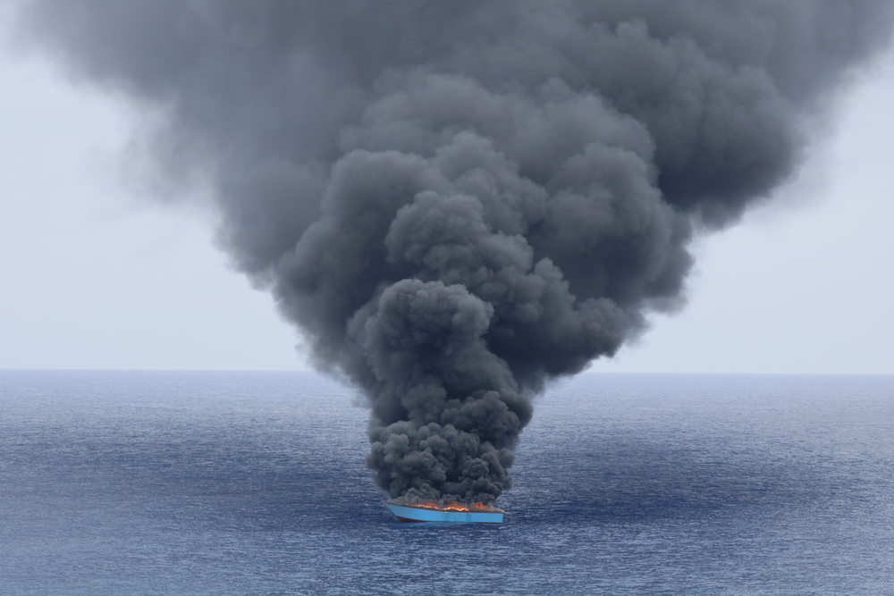 一艘木船被利比亞海岸衞隊攔截後冒出黑煙。船上約有 50 人，他們在木船起火前已被轉移到海岸衞隊的船上。© SKYE MCKEE/MSF