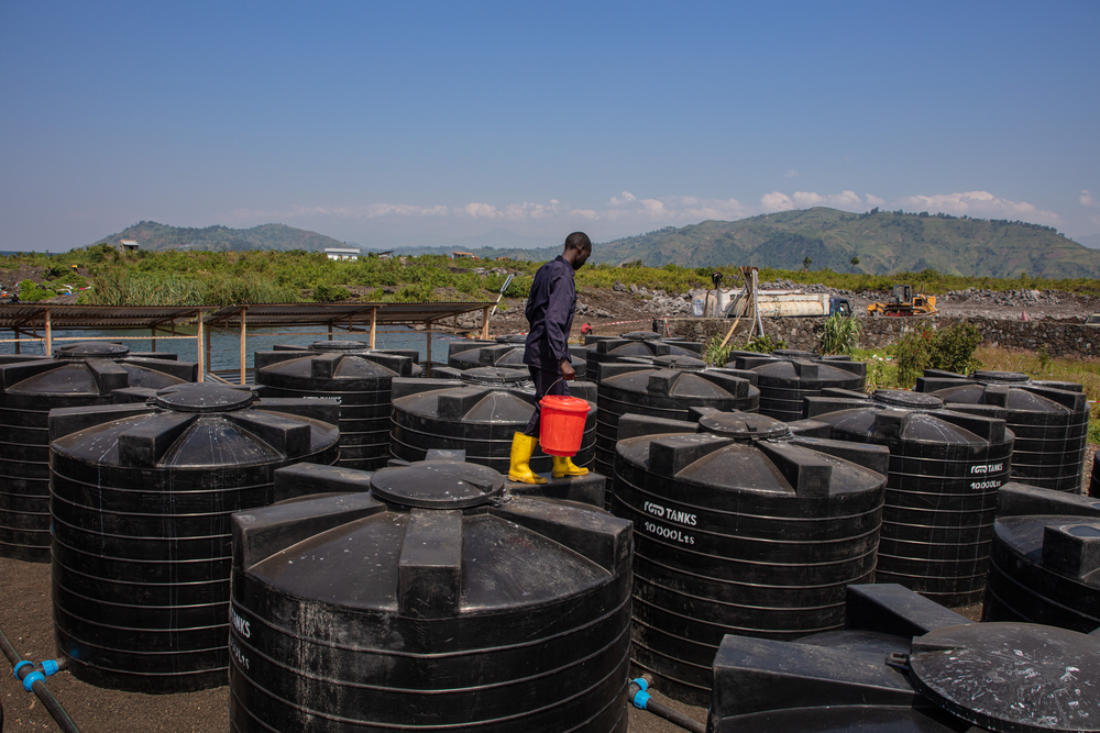 An MSF water and sanitation hygienist walks across the top of water tanks being used to store and treat water for the people living in Bulengo displaced people’s camp. © ALEXANDRE MARCOU/MSF