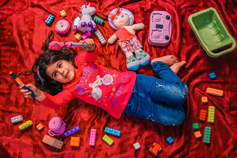 Siwar holds up her insulin pen while lying down among her toys in her family's makeshift home. Siwar was diagnosed with type 1 diabetes at a young age and frequents the MSF clinic in town for treatment. © CARMEN YAHCHOUCHI/MSF
