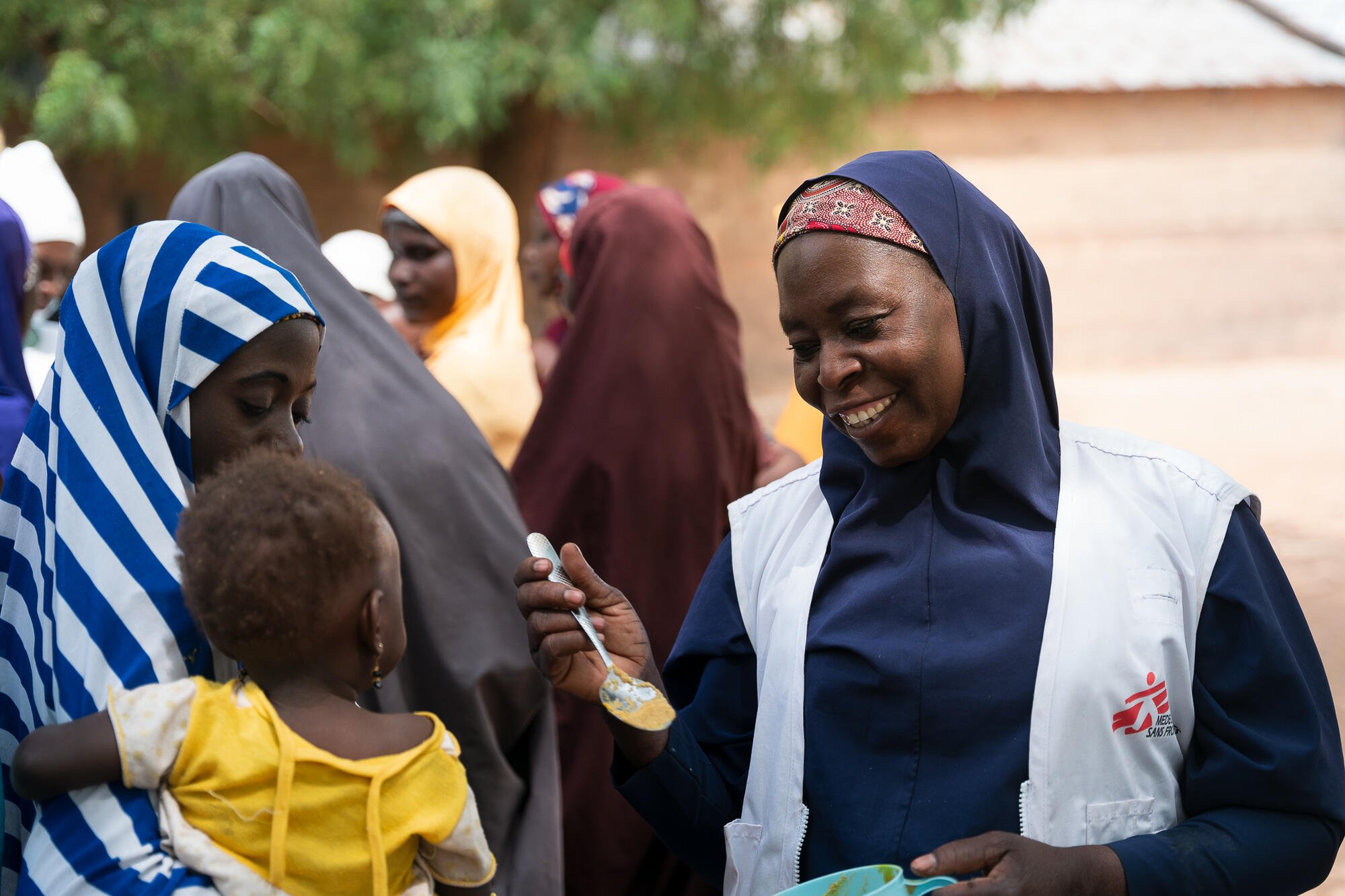 Maryam Muhammad, MSF health promotion supervisor in Kebbi, gives a spoon of Tom Brown to a child. © Georg Gassauer/MSF