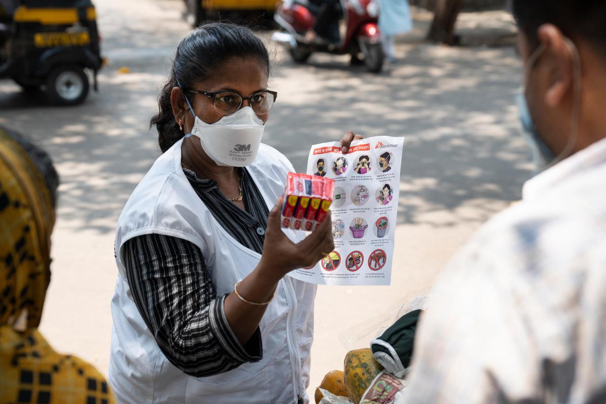 一名社區健康推廣員在孟買街頭向一名小販講解正確配戴口罩的方法。©Premananda Hessenkamp 