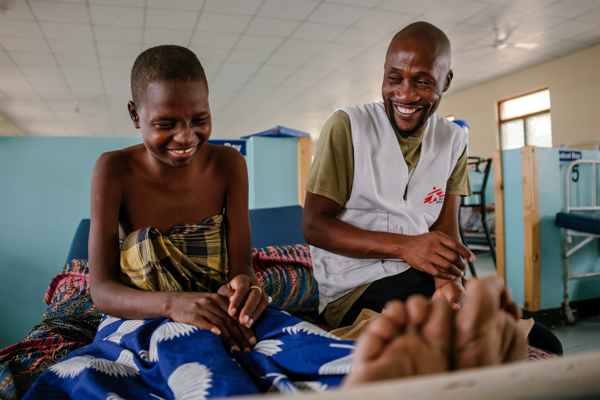 Esther, an advanced HIV patient interacting with Moses Luhanga, MSF Information Education and Communication Manager. In the picture, Moses is finding out how Esther is feeling. © Isabel Corthier/MSF