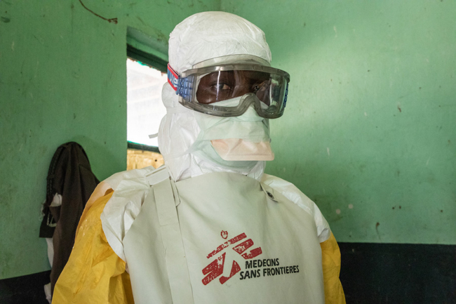An MSF team member gets dressed into a full protective suit. Photo: Louise Annaud/MSF