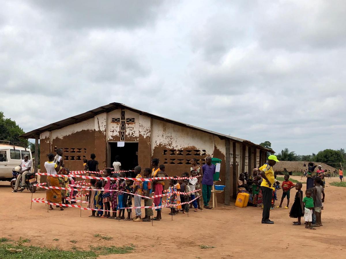 剛果民主共和國一間教堂前，數個家庭正等候接種麻疹疫苗。醫療隊設立特別的排隊線，以保持各家庭之間的距離，作為2019冠狀病毒病的預防措施之一。© MSF/Carol Bottger