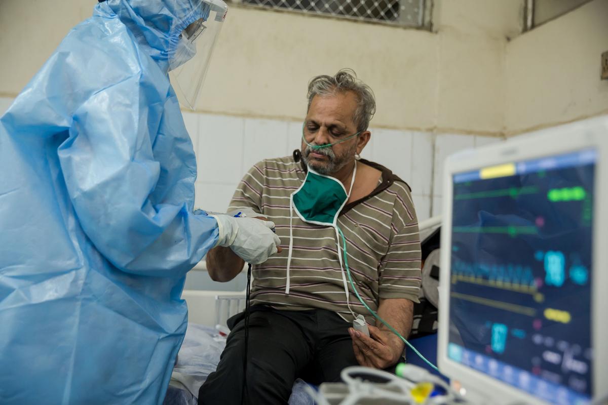 印度孟買一間醫院的指定2019冠狀病毒病健康中心的病房內，一名醫生正以高流量氧氣鼻導管儀器，為病人提供治療。© Abhinav Chatterjee/MSF